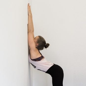 Alicia performing a wall back stretch 