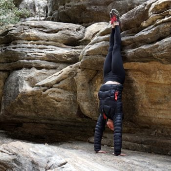 athlete performing a handstand outdoors against boulders