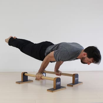 Ryan doing an arm lever exercise on parallettes