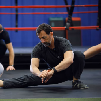 Burpees Don’t Have to Suck: Stop Chasing Reps and Start Training Smarter 3 A man moving through a Cossack squat as a burpee variation